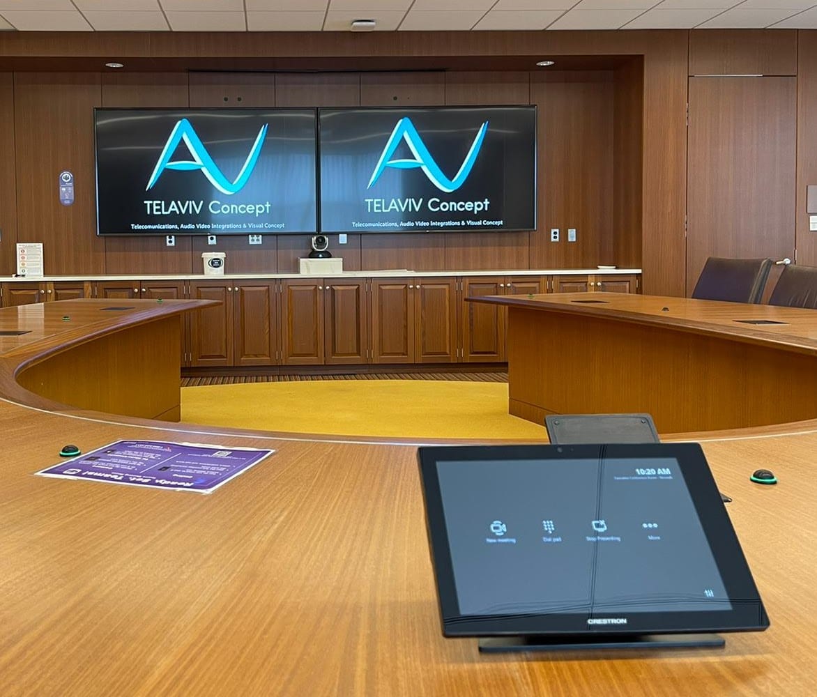 Conference room with two wall displays, a conferencing camera between them and a touch panel on the table